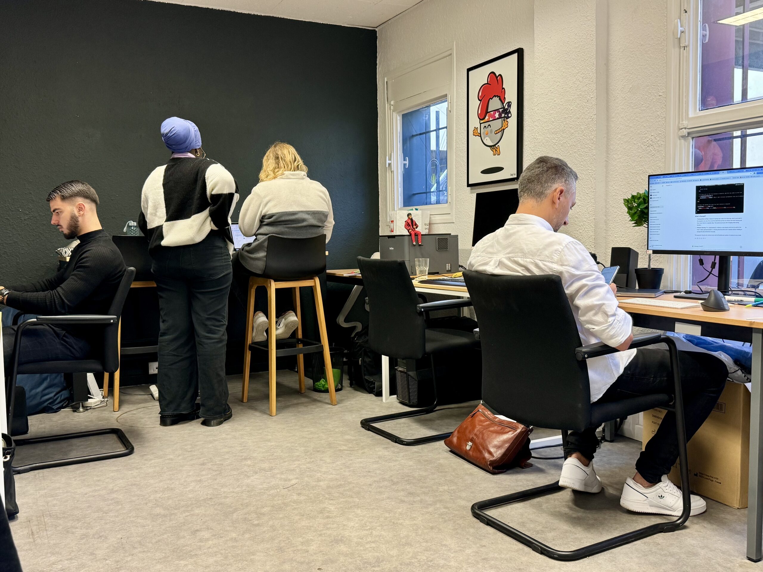Quatre personnes installées autour de bureaux et d’ordinateurs dans l’espace de travail partagé.