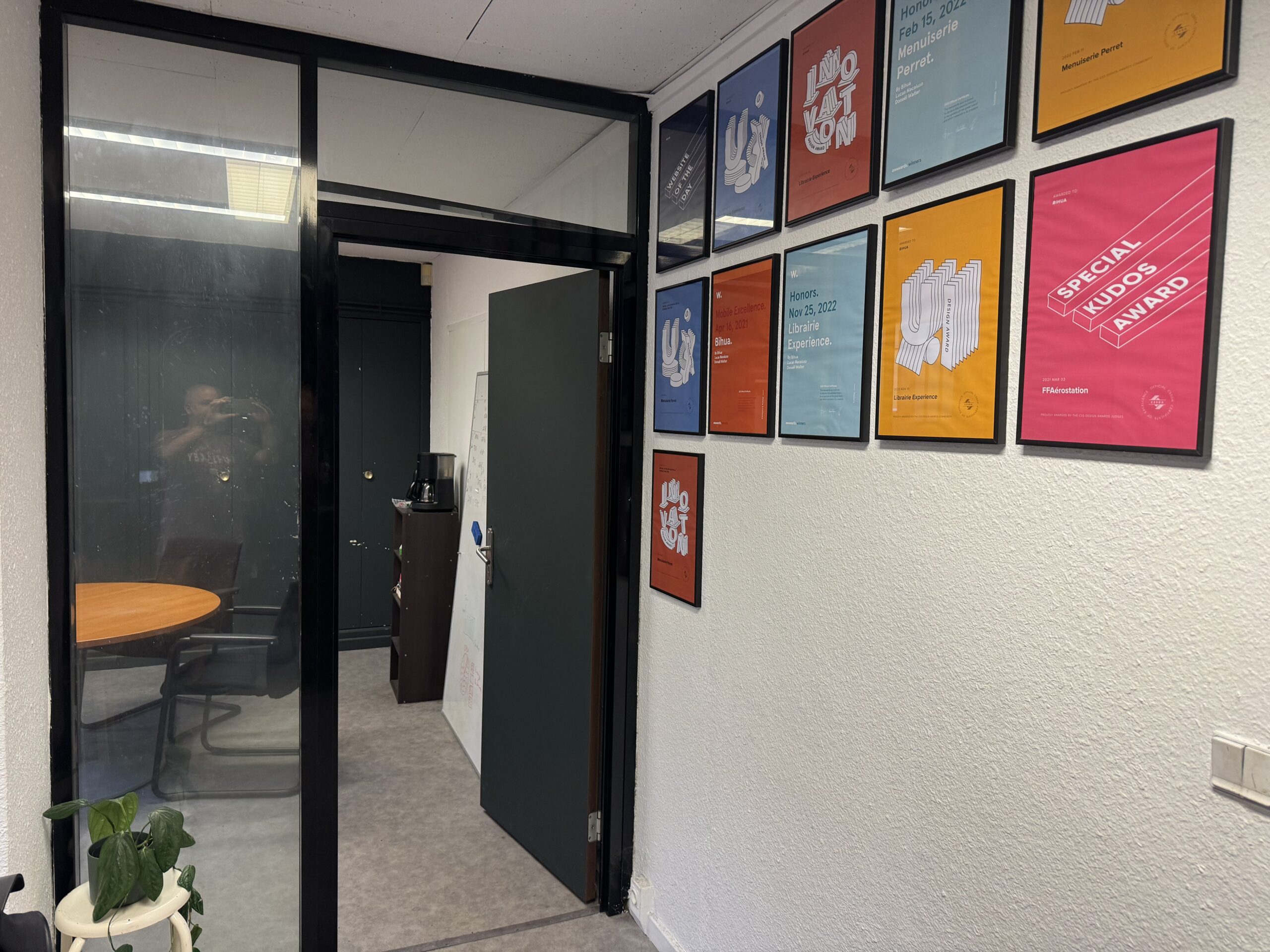 Entrée vitrée de la salle de cours, à côté d’un mur de cadres colorés.